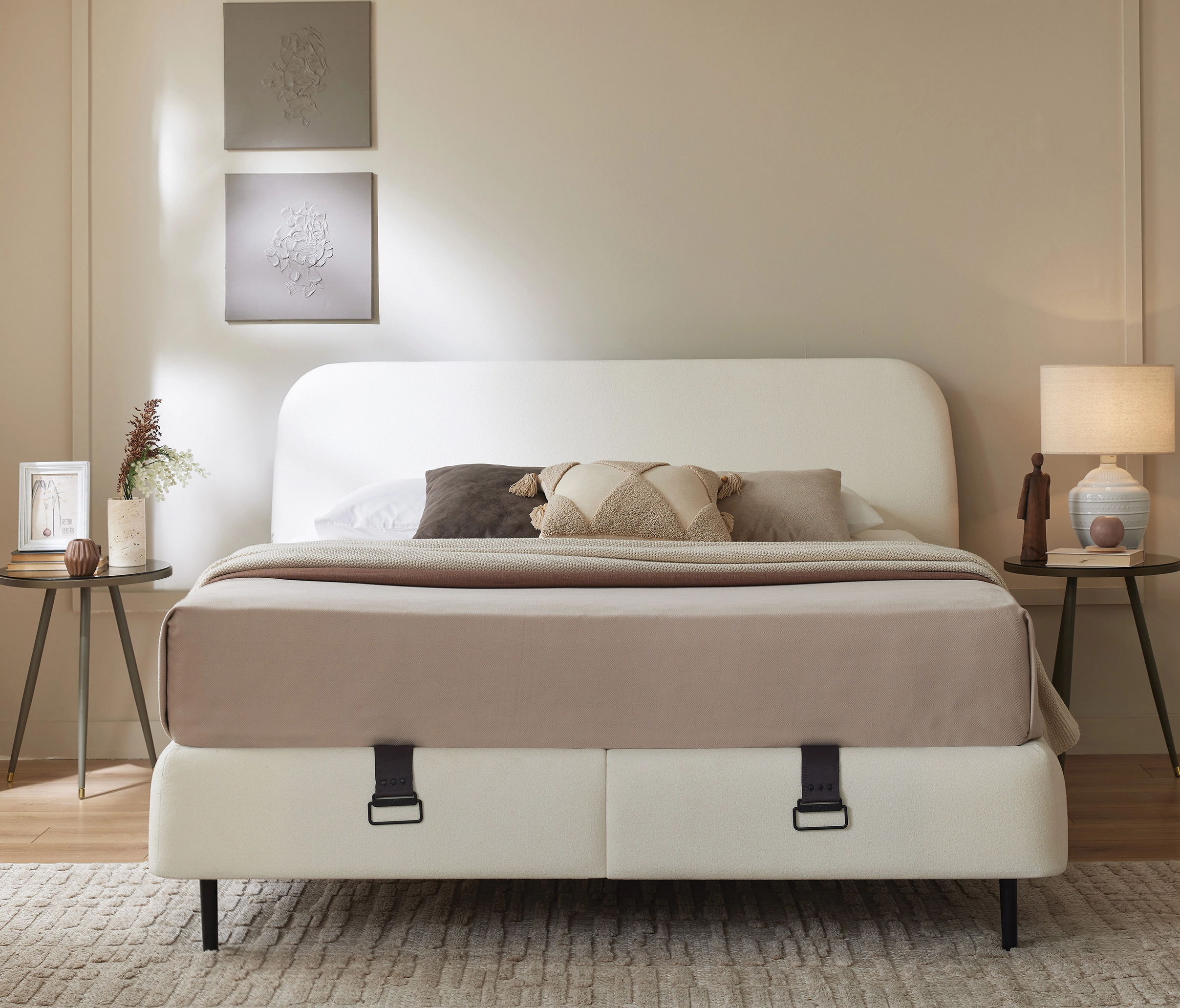 Sommier coffre Prime écru avec tête de lit arrondie, pieds métal noirs, linge de lit beige et coussins