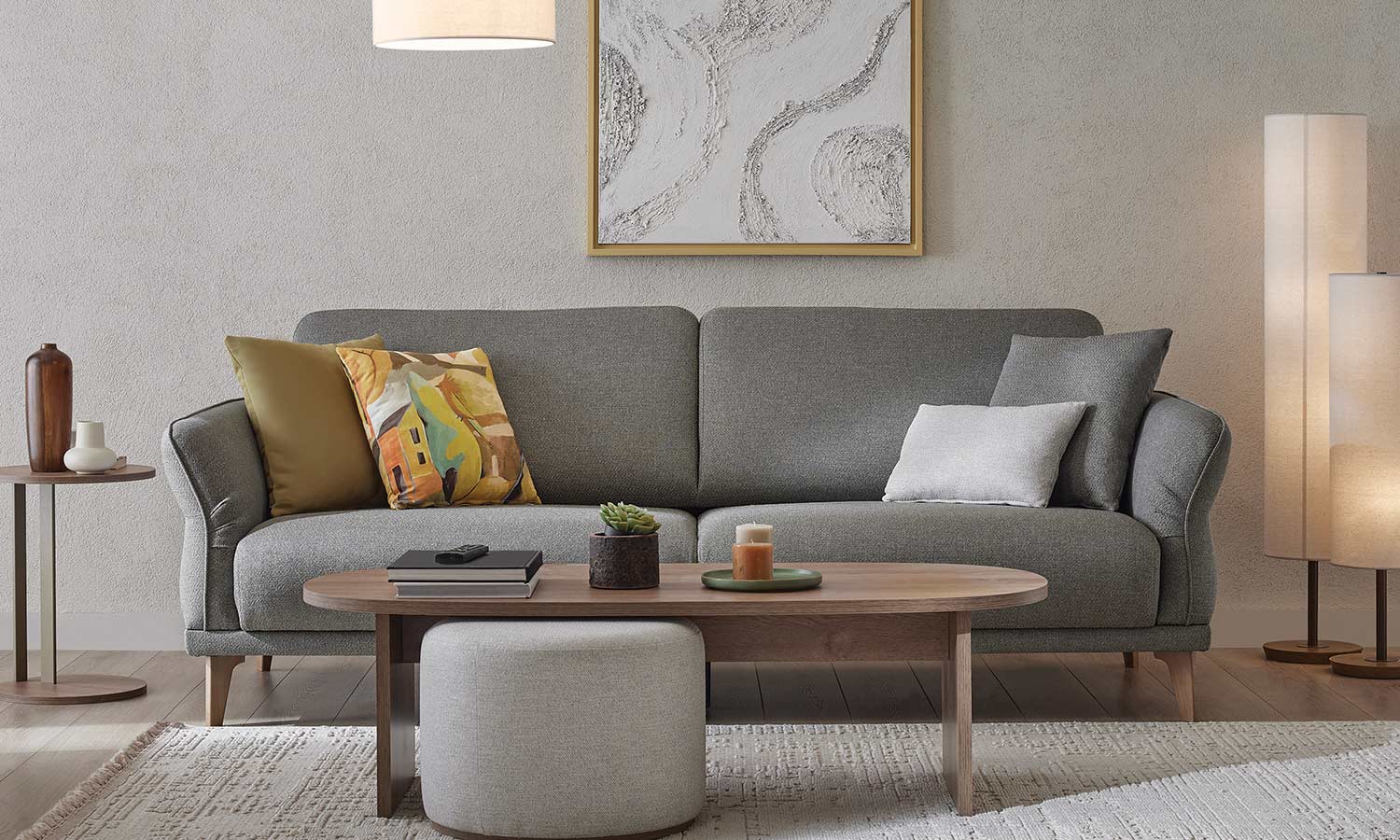 Canapé Veneta gris avec coussins déco moutarde et imprimé, dans un salon avec table basse ovale en bois