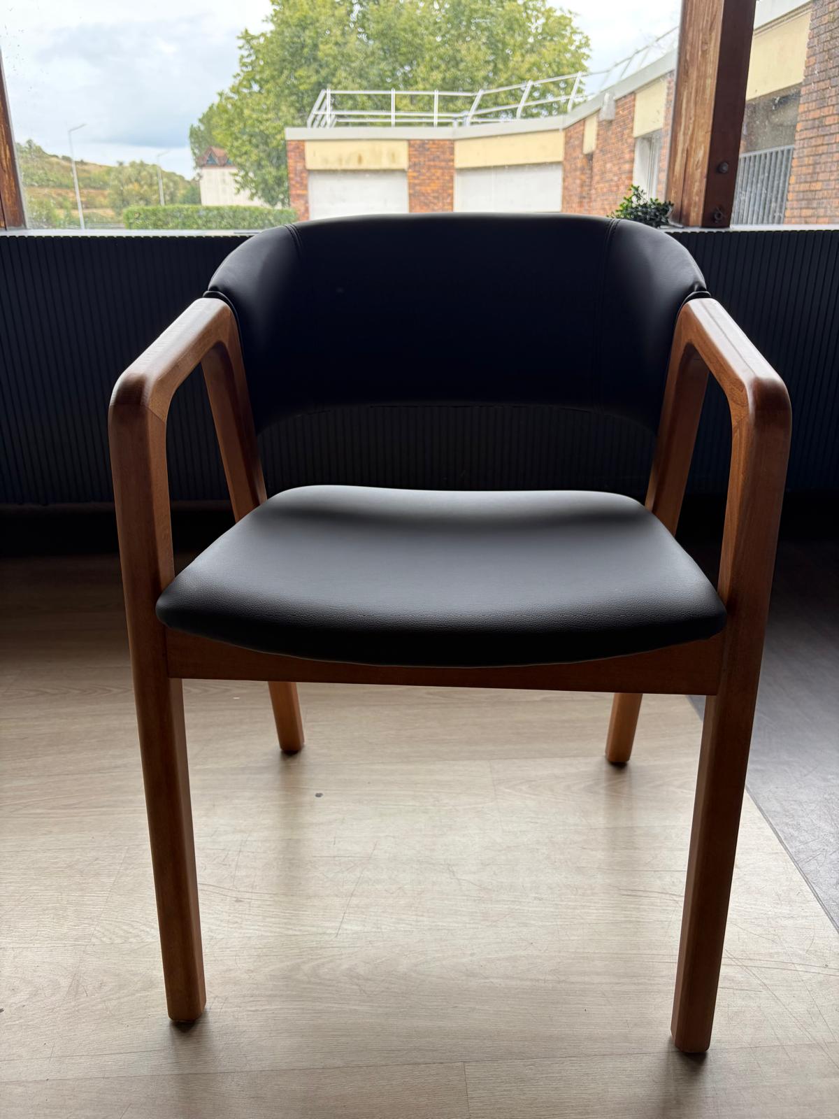 Chaise avec accoudoirs en bois clair et assise/dossier en simili cuir noir, vue de face