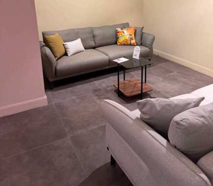 Canapé Veneta gris avec coussins moutarde, blanc et imprimé coloré, table basse en bois et verre, showroom AF Mobilier