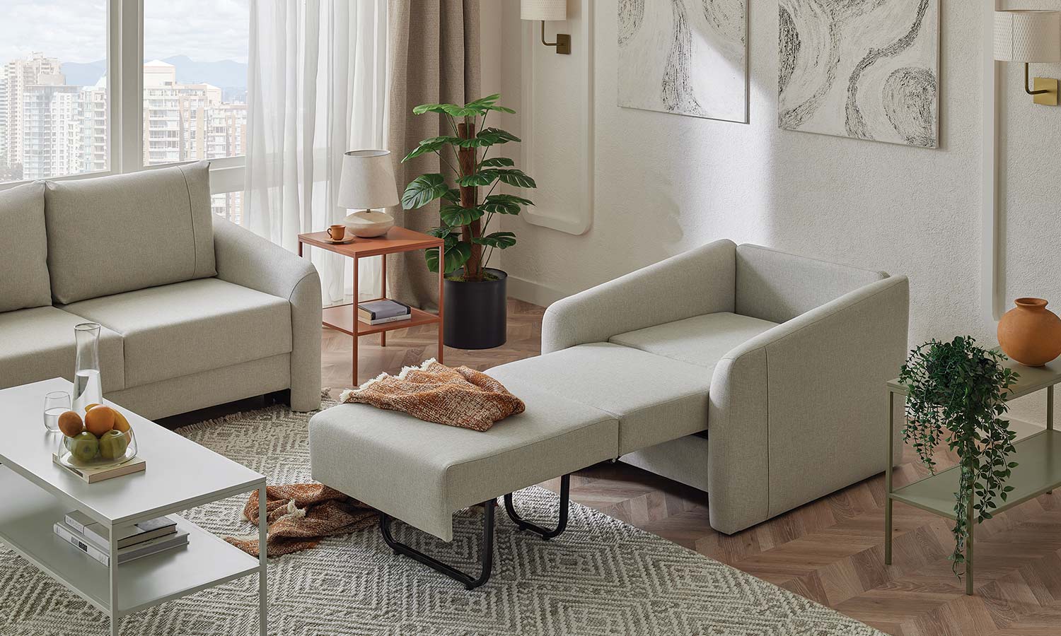 Fauteuil Ester gris clair déplié en couchage individuel, avec plaid orange, à côté du canapé 2 places