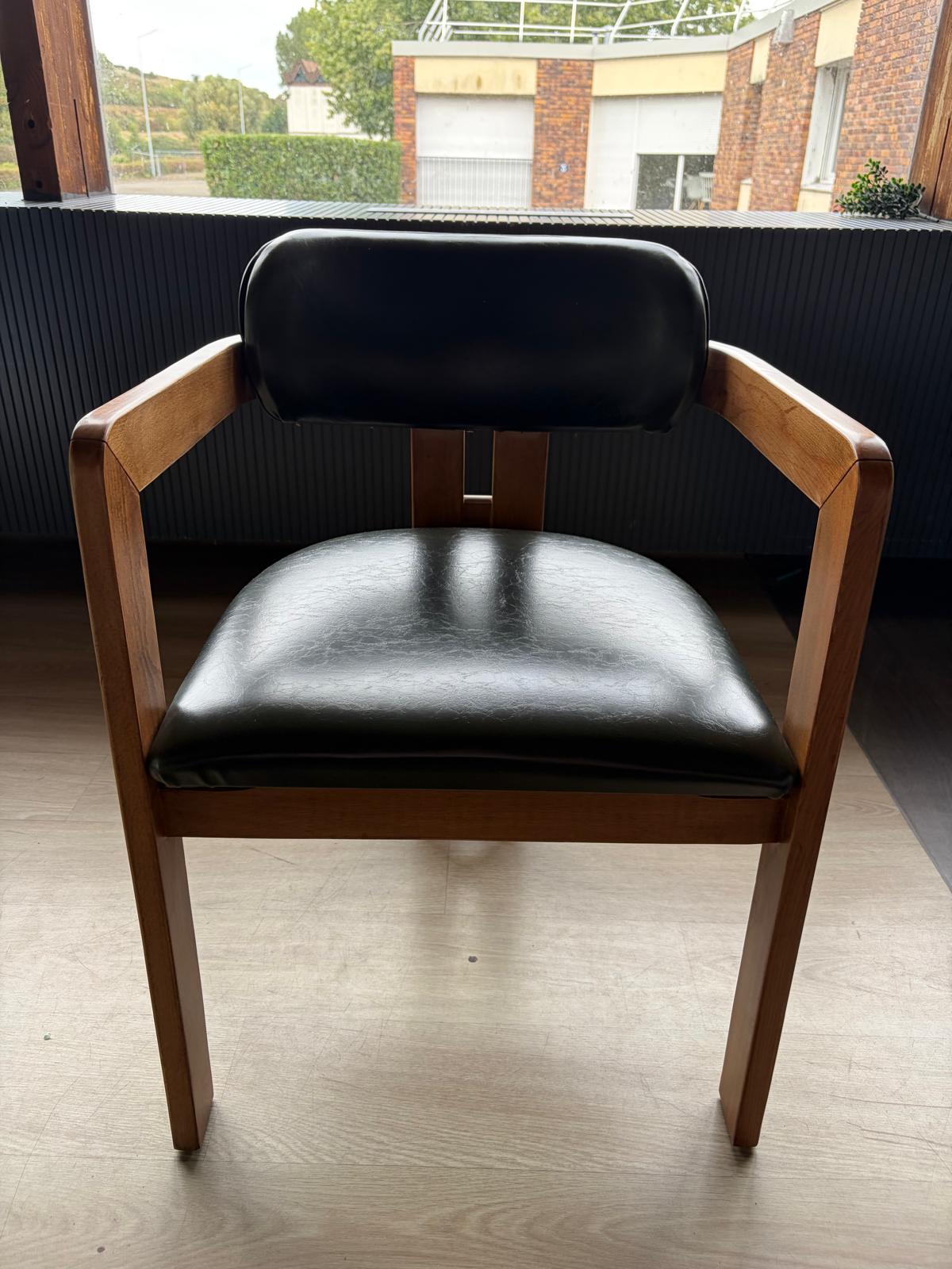 Chaise bois clair avec assise et dossier en simili cuir noir, dossier droit avec pieds arrière en bois visibles, vue de face
