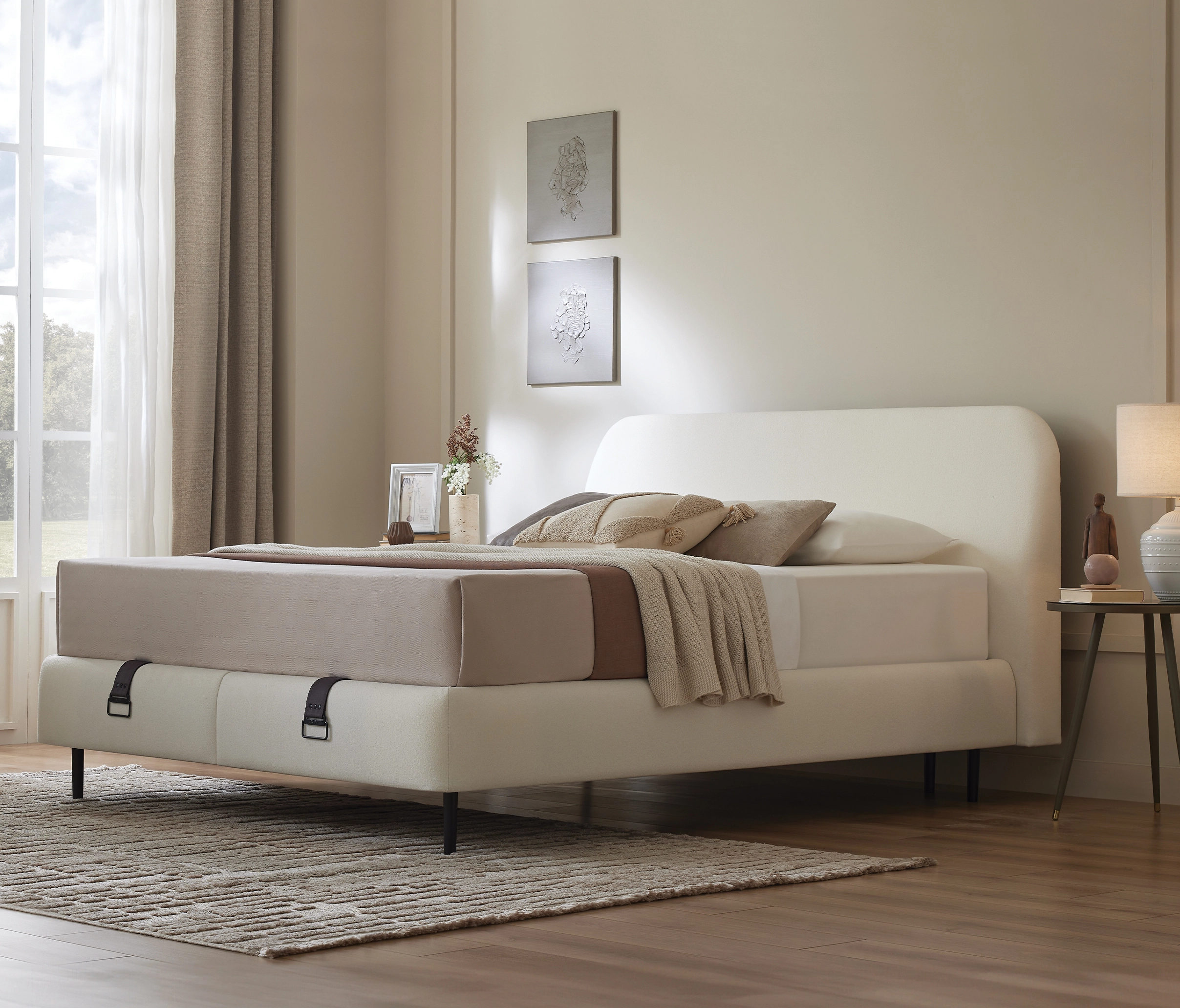 Sommier coffre Prime écru avec tête de lit arrondie, chambre beige avec table de chevet et lampe