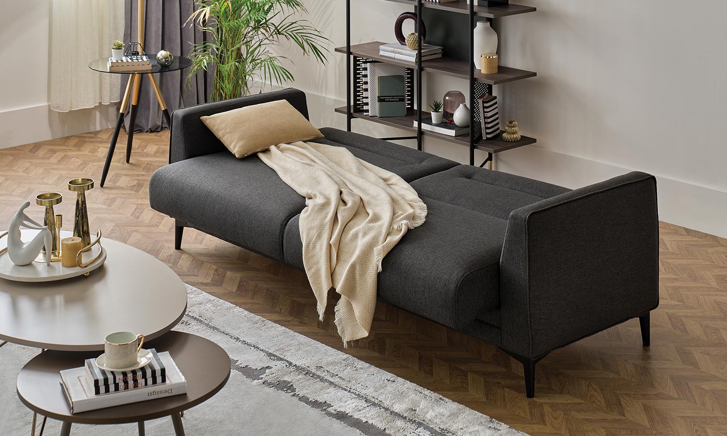 Canapé Calis gris anthracite déplié en lit, avec plaid beige et coussin