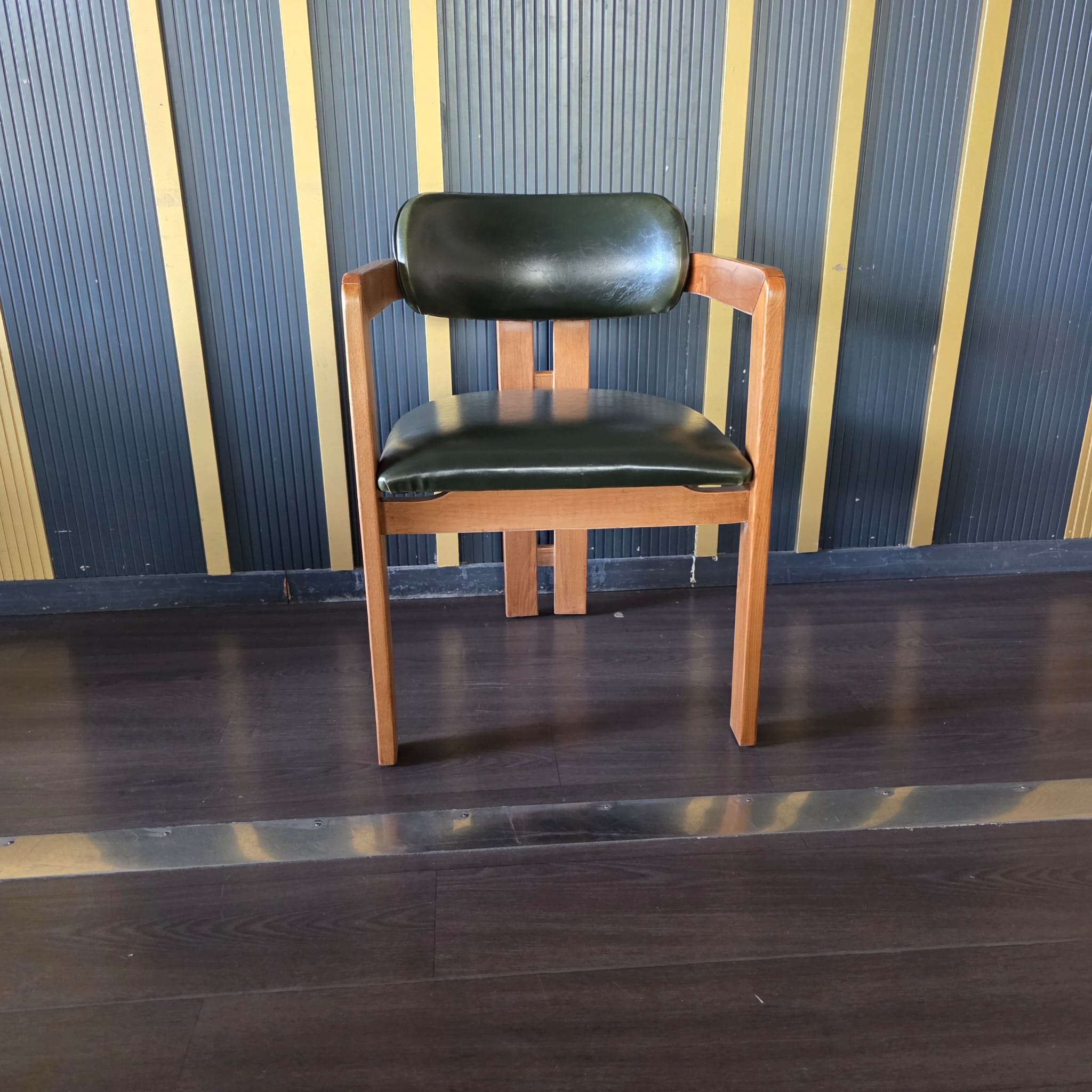 Chaise en bois avec accoudoirs et assise/dossier en simili cuir vert foncé, dossier à structure en bois apparente