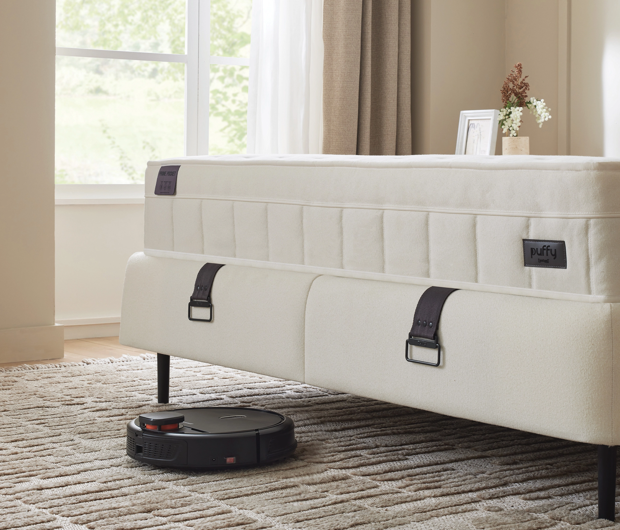 Gros plan sur les sangles noires du sommier Prime et pied fin, matelas Puffy, robot aspirateur passant dessous