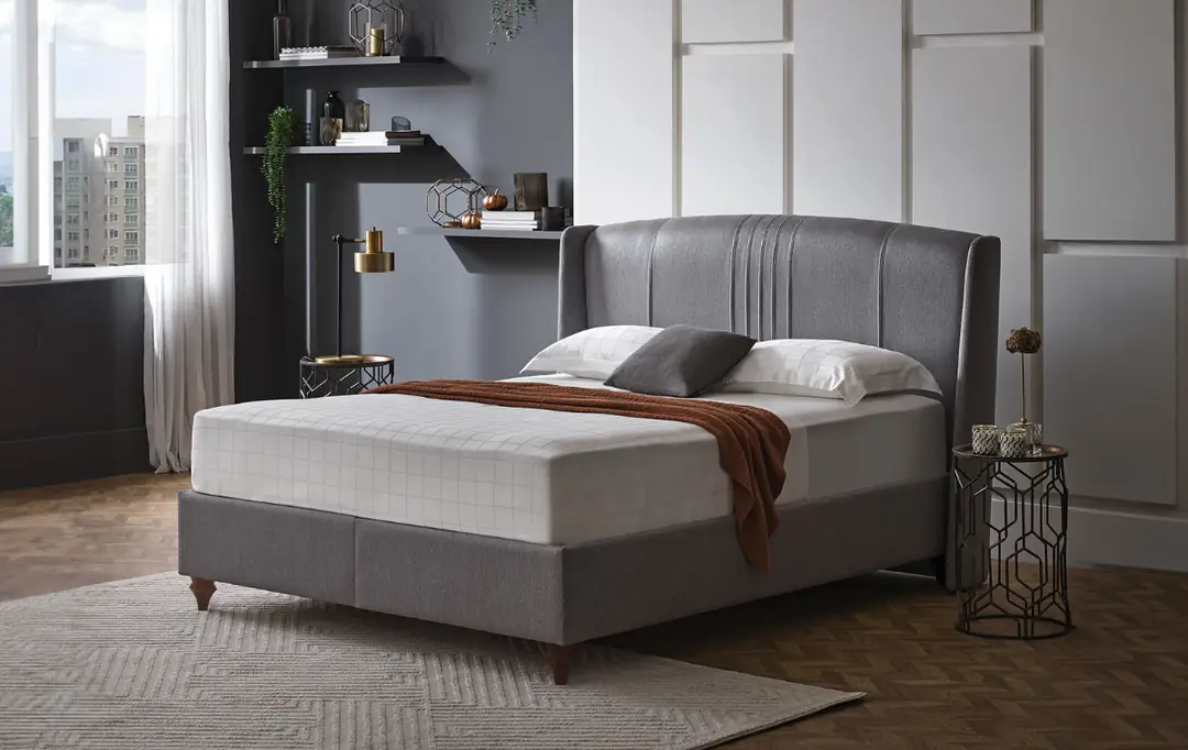 Lit Ronda gris avec tête de lit capitonnée à cannelures, plaid marron, chambre avec étagères et table d'appoint dorée